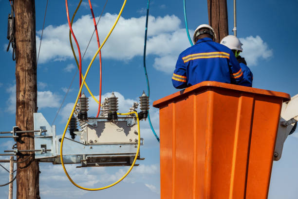 Two African electrician workers climbed on the pole repairing an electric line